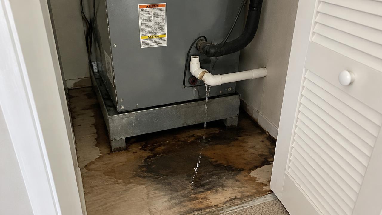 Indoor AC air handler leaking condensate water onto a closet floor